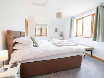a bedroom with a large bed with white sheets and pillows at Cwmwr in Pen-y-bont-fawr