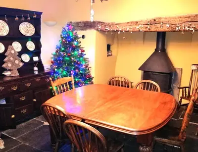 a dining room with a wooden table and a christmas tree at Glan y Morfa Welsh farmhouse overlooking Dyfi Estuary Rated 4 star Visit Wales in Pennal