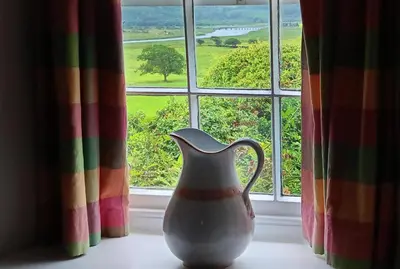 a vase sitting on a windowsill in front of a window at Glan y Morfa Welsh farmhouse overlooking Dyfi Estuary Rated 4 star Visit Wales in Pennal