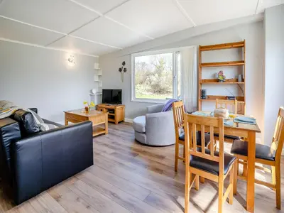 a living room with a table and a dining room at Tynrhos Lake View in Cilcennin