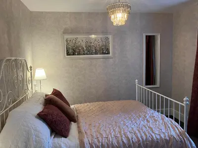 a bedroom with a white bed and a chandelier at Divine, detached countryside cottage near Ludlow. in Ludlow
