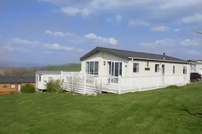 a white house with a white fence in a yard at Bay View Lodge, Brynowen in Borth