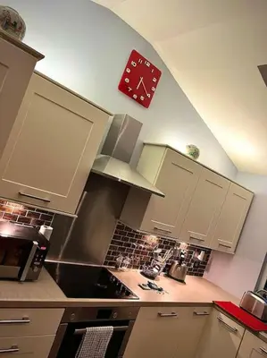 a kitchen with a clock on the wall above a stove at Countryside in the Town. in Harlescott
