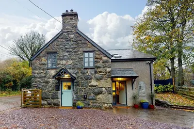 a stone house with a blue door on a driveway at Ysgoldy in Llanfor