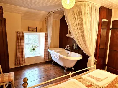 a bathroom with a tub and a sink and a window at Arwel in New Quay