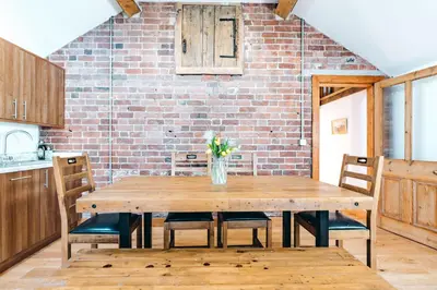a wooden table in a kitchen with a brick wall at ryton grange church barn sleeps 5 in Shrewsbury