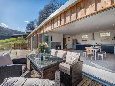 a patio with a table and chairs and a kitchen at Larchwood Lodge in Old Radnor