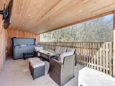 a patio with a table and chairs on a deck at Larchwood Lodge in Old Radnor