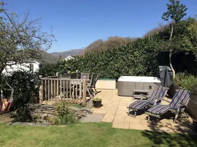a patio with two chairs and a fence at Lovely cottage in Snowdonia, private hot tub, by mountains & award winning beach in Fairbourne