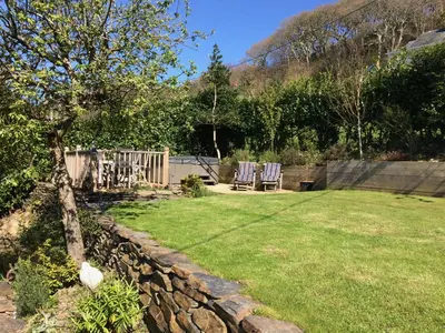 a yard with two chairs and a stone wall at Lovely cottage in Snowdonia, private hot tub, by mountains & award winning beach in Fairbourne