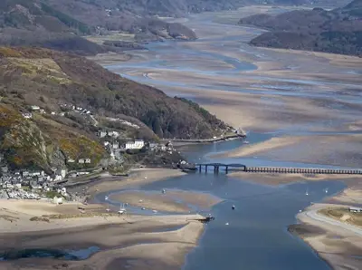 an aerial view of a river with a bridge at Lovely cottage in Snowdonia, private hot tub, by mountains & award winning beach in Fairbourne