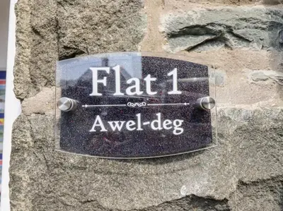 a sign on a stone wall with the name of a dog at Harlech/HUGE Three bedroom/BEST location in Llanbedr