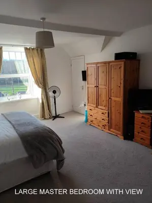 a large master bedroom with a bed and a window at Harlech/HUGE Three bedroom/BEST location in Llanbedr