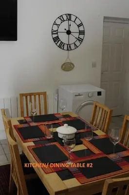 a dining room table with a clock on the wall at Harlech/HUGE Three bedroom/BEST location in Llanbedr