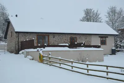 a house covered in snow with a fence in front of it at Stone Cottage in Shrewsbury