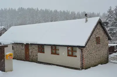 a house covered in snow with trees in the background at Stone Cottage in Shrewsbury