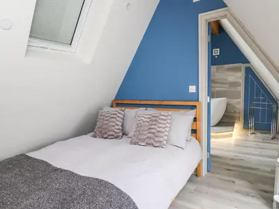 a bedroom with a bed and a blue wall at Hill Radnor - The Sheepfold in Llandrindod Wells