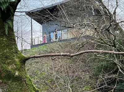 two people standing on a building on a hill at Luxury Lodge In The Treetops in Llanbrynmair