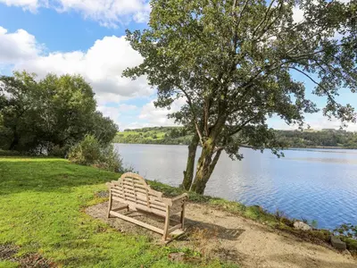 a bench sitting on the grass next to a lake at Drysgol Lakeside - Bala Lake in Bala