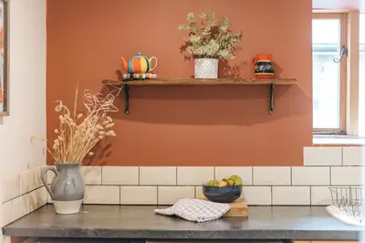 a kitchen with orange walls and a counter with a table at The Grain Loft in Clun