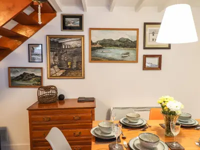 a dining room with a wooden table and paintings on the wall at Deu-Ddrws in Barmouth