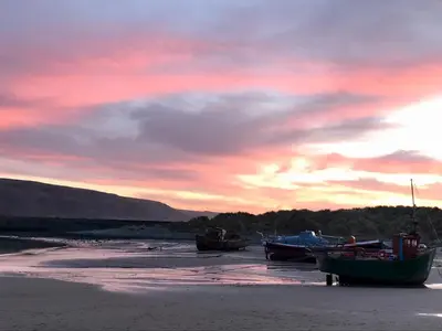 a group of boats sitting on the beach at sunset at Deu-Ddrws in Barmouth