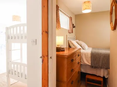 a bedroom with a bed and a wooden dresser at Deu-Ddrws in Barmouth