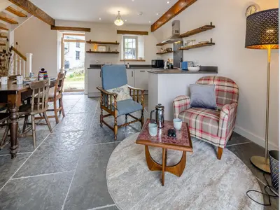 a living room and kitchen with a table and chairs at Ivy Bush Cottage in Llanddewi-Brefi