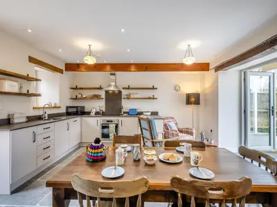a kitchen and dining room with a wooden table and chairs at Ivy Bush Cottage in Llanddewi-Brefi