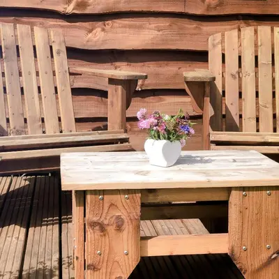 a wooden table with a vase of flowers on it at Shire the Shepherd's Hut at Pentref Luxury Camping in Penuwch