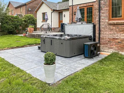 a patio with a hot tub and a tv on a yard at Dyffryn Cain in Aberystwyth