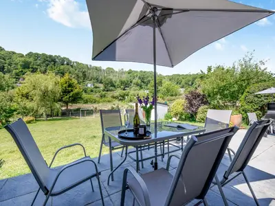 a table and chairs with an umbrella on a patio at Dyffryn Cain in Aberystwyth
