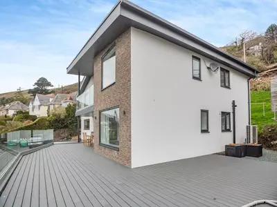 a house with a large deck in front of it at Bodwennol - a stunning house! in Aberdyfi