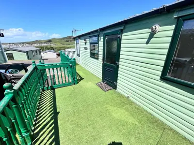 a green house with a porch and a door at Van number 123 Beautiful Caravan sleeps 4 in Aberystwyth
