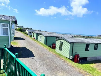 a row of green mobile homes on a gravel road at Van number 123 Beautiful Caravan sleeps 4 in Aberystwyth