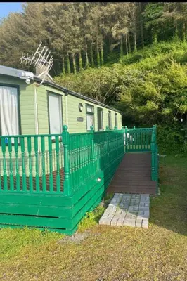 a green fence in front of a house at Van number 123 Beautiful Caravan sleeps 4 in Aberystwyth