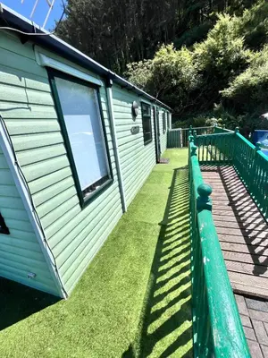 a green fence next to a tiny house at Van number 123 Beautiful Caravan sleeps 4 in Aberystwyth