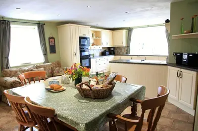 a kitchen with a table with chairs and a counter top at Llanhedric House in Clun