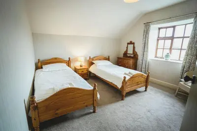 two twin beds in a bedroom with a window at Llanhedric House in Clun