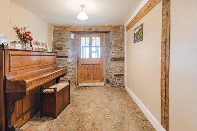 a hallway with a wooden piano and a door at Llanhedric House in Clun