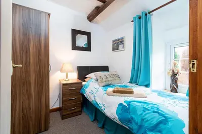 a bedroom with a bed and a window with blue curtains at Pant in Llanymawddwy
