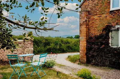 two blue chairs sitting next to a brick building at The Coach House Barn in Shrewsbury