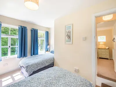 two beds in a bedroom with blue curtains at Jackdaw Cottage in Knighton