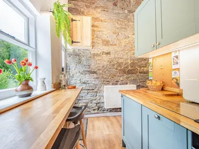 a kitchen with a wooden counter and a stone wall at Jackdaw Cottage in Knighton