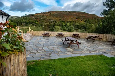 a stone patio with picnic tables and a fence at The Berwyn Arms in Corwen