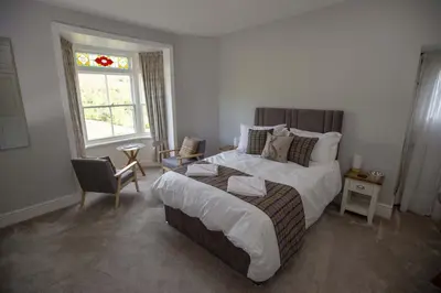 a bedroom with a bed and a chair and a window at The Berwyn Arms in Corwen