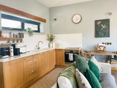 a living room with a couch and a kitchen at The Tin Shed in Rhayader