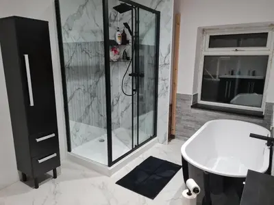 a bathroom with a shower and a tub and a sink at Cosy Riverside home in Llanwrda