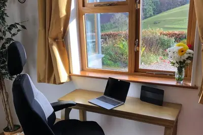 a desk with a laptop on it next to a window at 3-Bed Cottage Near Lake Vyrnwy Garden & PetsOk in Hirnant