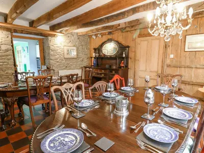 a dining room with a table and chairs and a clock at Cringoed House in Aberaeron